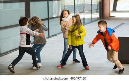 Happy Kids Running Around While Playing At Tag In Street