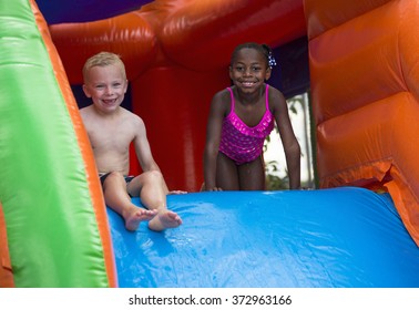 Happy kids sliding down an inflatable bounce house 
