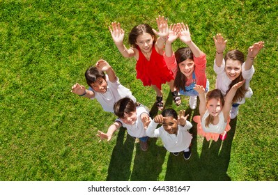 Happy kids standing on grass and waving hands