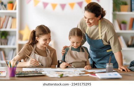 Happy kids and teacher at the art class. Woman and children are painting together. - Powered by Shutterstock