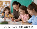 Happy kids and teacher at school. Woman and children are working in the class.