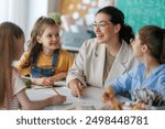 Happy kids and teacher at school. Woman and children are working in the class.