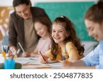 Happy kids and teacher at school. Woman and children are working in the class.