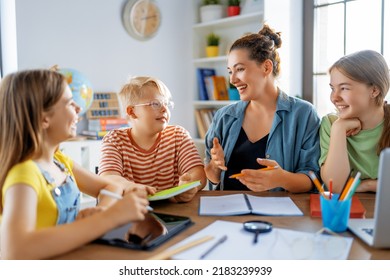 Happy Kids And Teacher At School. Woman And Children Are Talking In The Class.