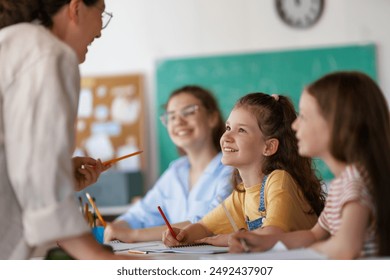 Happy kids and teacher at school. Woman and children are working in the class. - Powered by Shutterstock