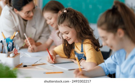 Happy kids and teacher at school. Woman and children are working in the class.