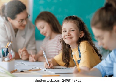 Happy kids and teacher at school. Woman and children are working in the class. - Powered by Shutterstock