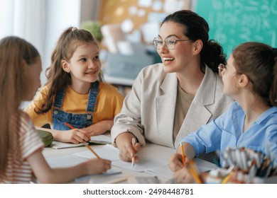 Happy kids and teacher at school. Woman and children are working in the class. - Powered by Shutterstock