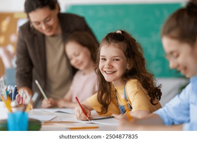 Happy kids and teacher at school. Woman and children are working in the class.