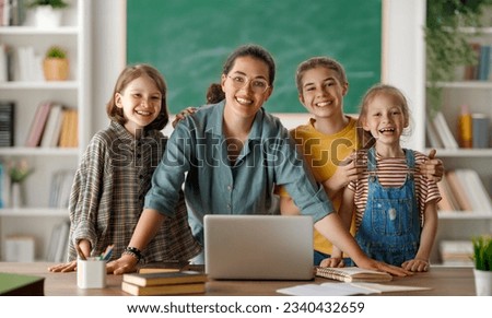 Happy kids and teacher at school. Woman and children are talking in the class.