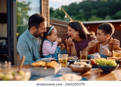 Happy kids and their parents eating donuts and having fun during family meal on a terrace.  - Powered by Shutterstock