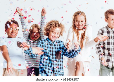 Happy kids throwing colorful confetti in a room - Powered by Shutterstock