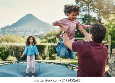 Happy kids, trampoline and jump in outdoor, playing and father helping in backyard of home. Children, daddy and energy for fun activity in childhood, garden and bounce movement for bonding together - Powered by Shutterstock