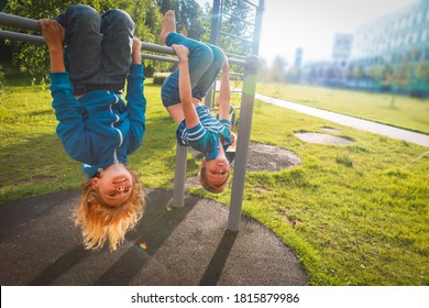 Happy Kids Upside Down On Monkey Bars Outdoors