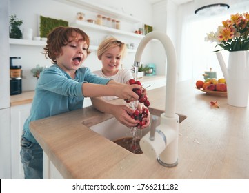 happy kids washing cherries under tap water in the kitchen - Powered by Shutterstock