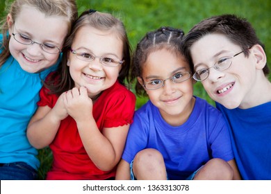 Happy Kids Wearing Glasses Sitting Together In Grass Outside - Portrait