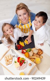 Happy Kids And Woman Preparing Healthy Breakfast Together - Top View