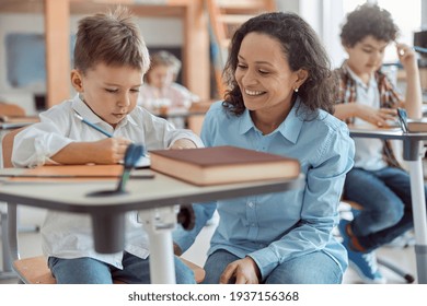 Happy kind teacher is helping a boy in elementary school lessons - Shutterstock ID 1937156368