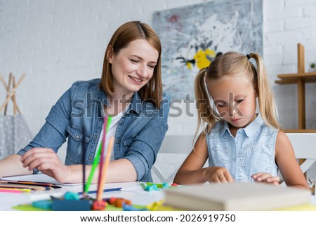happy kindergarten teacher looking at preschooler kid 