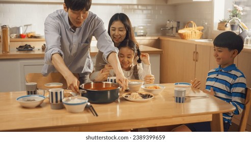 Happy Korean Family of Four Enjoying a Delicious Meal Together in Their Kitchen at Home. They are Sharing a Traditional Meal Made with Love and Care. Children Excited for Food - Powered by Shutterstock