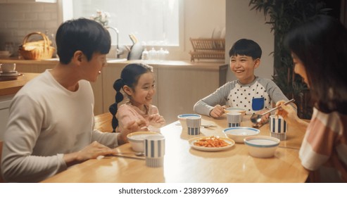Happy Korean Family Members Enjoying Delicious Food Together. Young Parents and Their Two Children Eating Traditional Dishes at Home While Sitting at Their Kitchen Table - Powered by Shutterstock