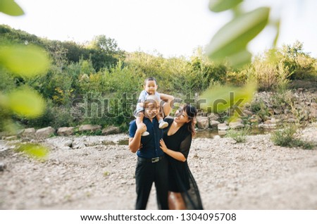 happy korean family on a walk near the river in the mountains, mom, dad and son asian laugh and hug
