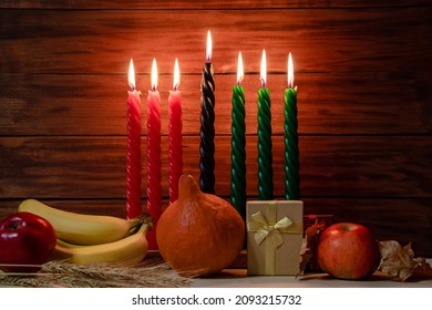 Happy Kwanzaa. Seven candles red, black and green on a natural wooden background. Harvest and gifts. Symbols of African heritage.