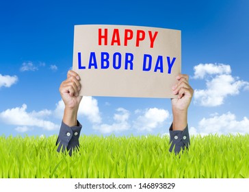 Happy Labor Day Cardboard With Man Hand Over Green Field And Blue Sky Background