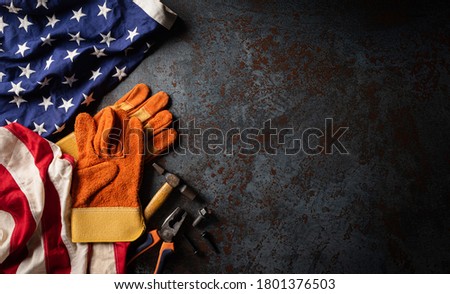 Happy Labor day concept. American flag with different construction tools on dark stone background, with copy space for text.