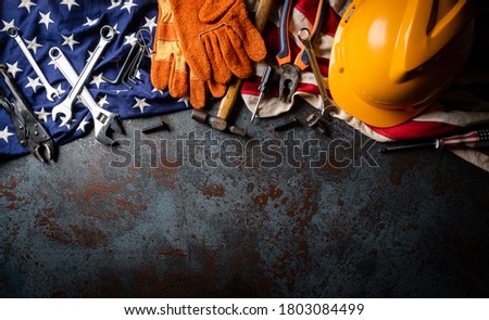 Happy Labor day concept. American flag with different construction tools on dark stone background, with copy space for text.