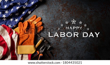 Happy Labor day concept. American flag with different construction tools on dark stone background, with copy space for text.