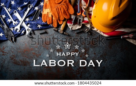Happy Labor day concept. American flag with different construction tools on dark stone background, with Happy Labor Day text.