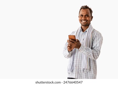 A HAPPY LABOURER LOOKING AT CAMERA WHILE USING MOBILE PHONE