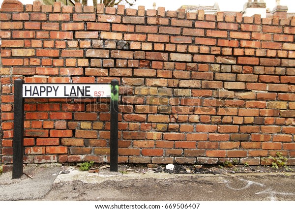 ハッピーレーン 英国のブリストルイギリスのレンガ壁の前にある クイルキーな道路標識 の写真素材 今すぐ編集