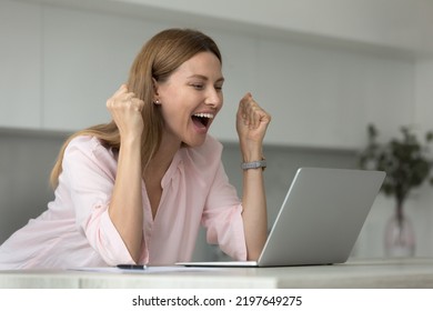 Happy Laptop User Woman Celebrating Good News, Success, Luck With Winner Yes Hands, Shouting For Joy At Laptop In Home Kitchen, Laughing, Feeling Excited, Surprise, Winning Prize