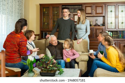 Happy Large Family Gathered In Parental Home For Family Party, Talking In Cozy Living Room