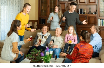 Happy large family gathered in parental home for family party, cheerfully talking in cozy living room - Powered by Shutterstock