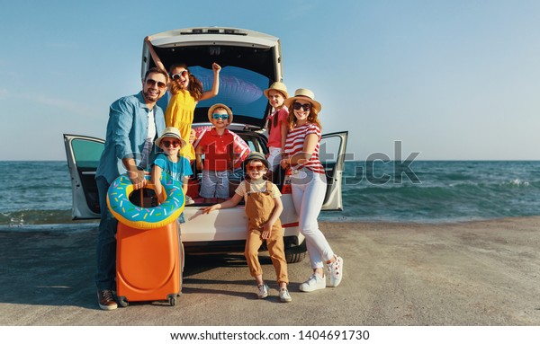 happy large family mother father\
and children in summer auto journey travel by car on\
beach\
