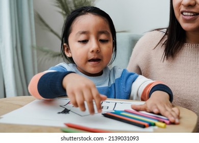 Happy latin american family having fun painting at home    Mother   son love concept    Focus kid face