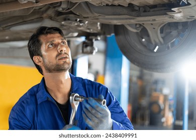 happy latin auto mechanic man checking tires , brakes under car with clipboard in garage cars service . hispanic technician repairing vehicle. lifted car checklist tyres and wheel in auto repair shop - Powered by Shutterstock