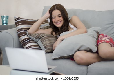 Happy latin brunette watching TV on her laptop