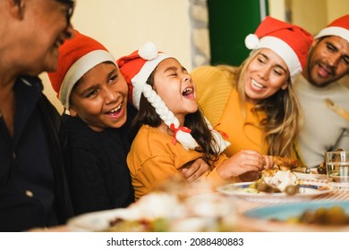 Happy latin family celebrating together during Christmas dinner - Focus on female kid face - Powered by Shutterstock