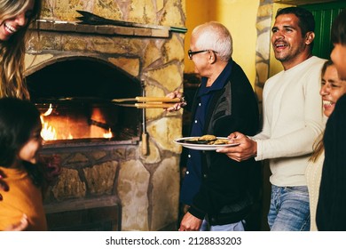 Happy latin family cooking together on wood bbq fireplace - Focus on father face