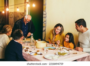 Happy Latin Family Cooking Together During Dinner Time At Home - Focus On Grandfather Face