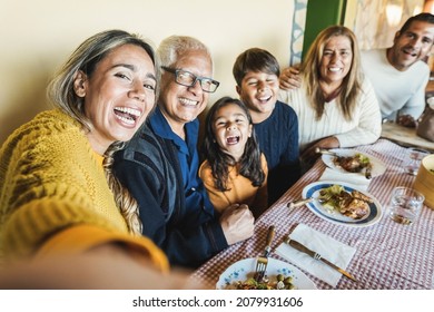 Happy latin family doing selfie while eating together at home - Focus on mother face - Powered by Shutterstock