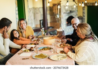 Happy latin family having fun eating together at vintage restaurant - Soft focus on grandmother head