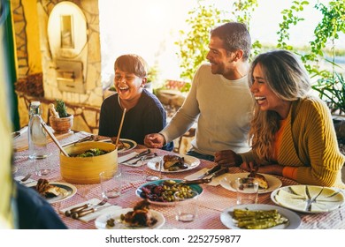 Happy latin family having fun eating together during home dinner - Soft focus on father hands - Powered by Shutterstock