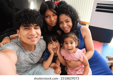 Happy latin family is making funny faces while taking a selfie at home - Powered by Shutterstock