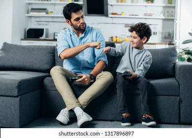 happy latin father giving fist bump to son after playing video game at home  - Powered by Shutterstock