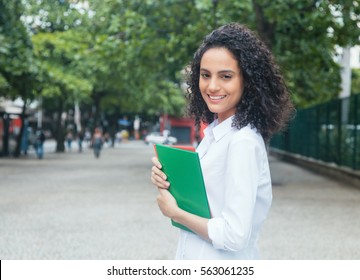 Happy Latin Female Student With Curly Hair And White Shirt